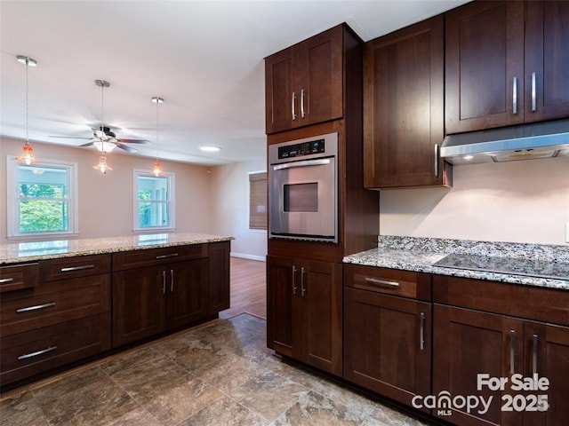 kitchen featuring dark brown cabinetry, black electric cooktop, under cabinet range hood, stainless steel oven, and pendant lighting