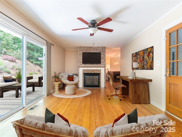 living area with ornamental molding, a fireplace, wood finished floors, and visible vents