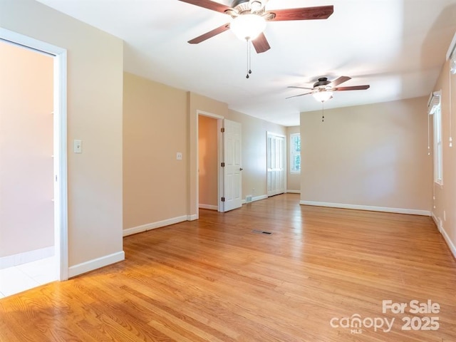 unfurnished room featuring a ceiling fan, light wood-type flooring, visible vents, and baseboards