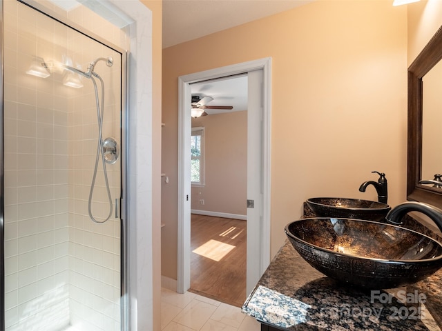 full bath with tiled shower, vanity, and baseboards