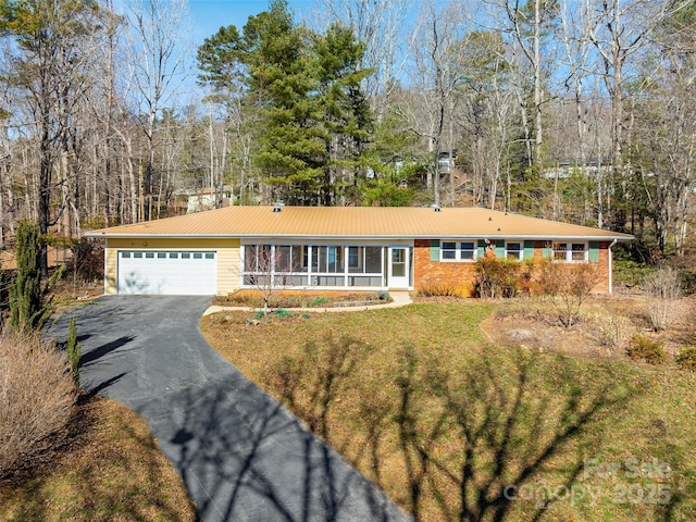 ranch-style house with aphalt driveway, an attached garage, and a front yard