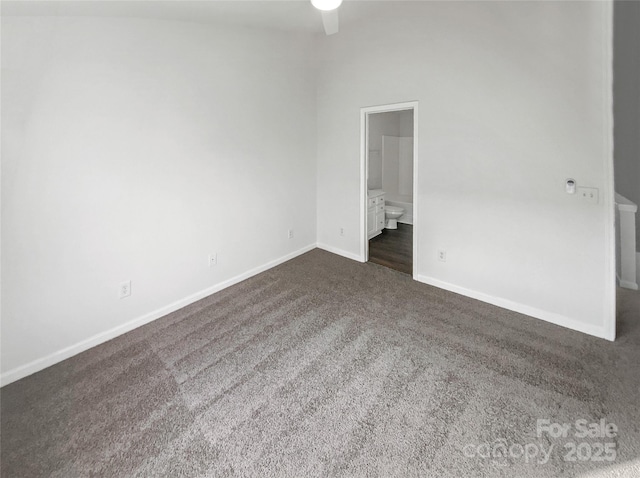 unfurnished bedroom with dark colored carpet, ensuite bath, and baseboards