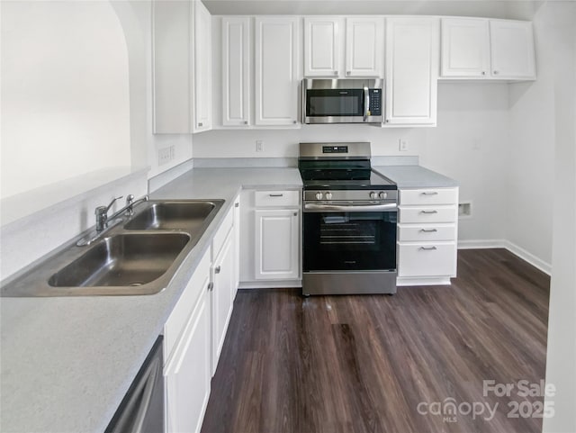 kitchen featuring appliances with stainless steel finishes, dark wood-style flooring, a sink, and white cabinetry