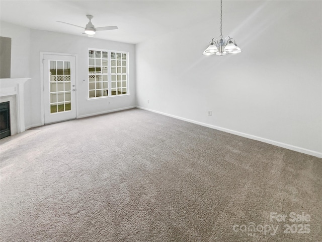 unfurnished living room featuring a premium fireplace, baseboards, carpet flooring, and ceiling fan with notable chandelier