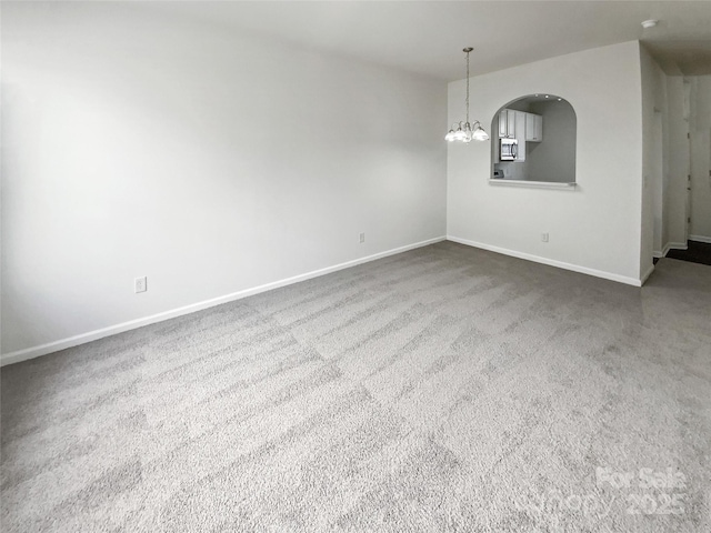 empty room featuring a chandelier and baseboards