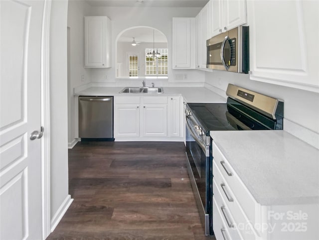 kitchen with dark wood-style floors, appliances with stainless steel finishes, a sink, and white cabinetry