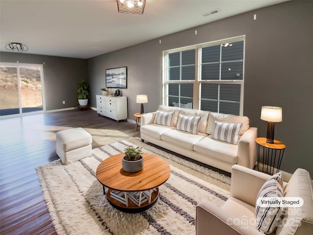 living room featuring baseboards, visible vents, and wood finished floors