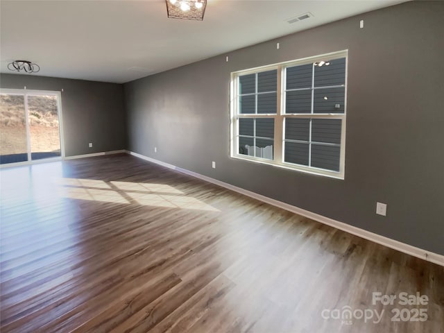 unfurnished room with visible vents, baseboards, and wood finished floors