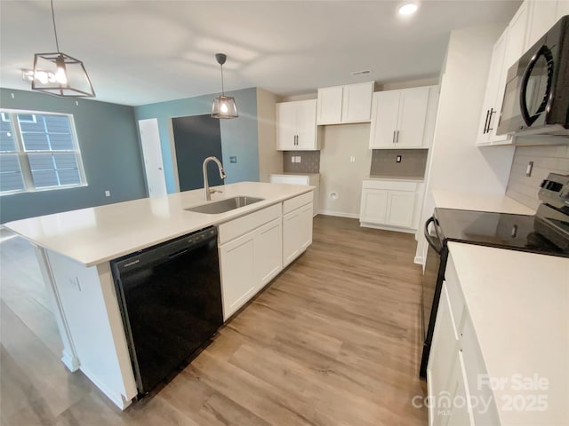 kitchen featuring light wood-style flooring, a sink, a kitchen island with sink, black appliances, and backsplash