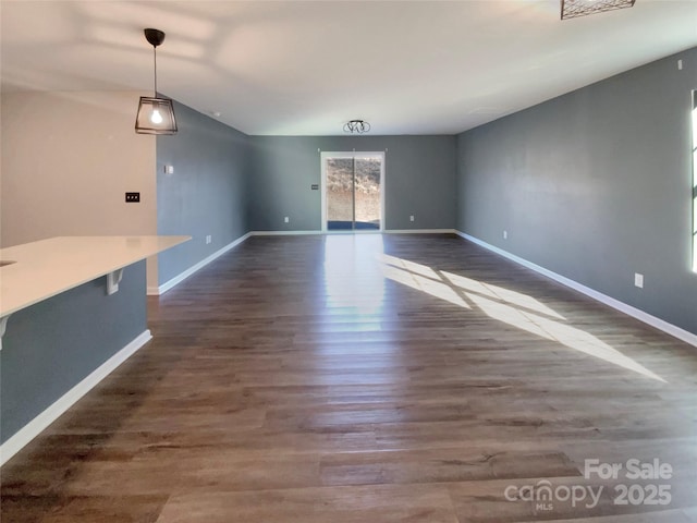 unfurnished dining area with dark wood-style floors and baseboards