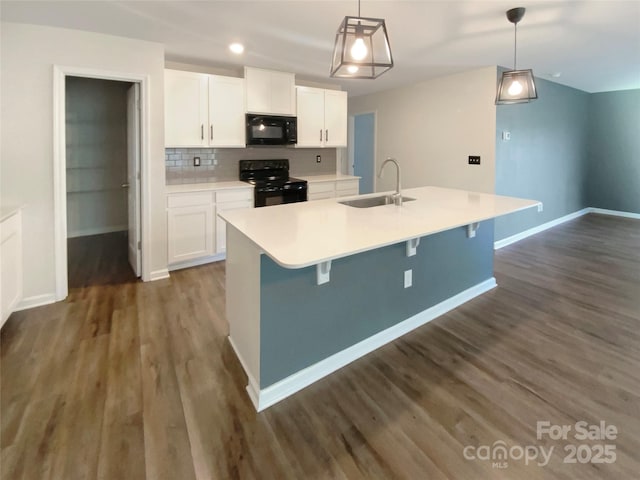 kitchen featuring dark wood finished floors, decorative backsplash, white cabinets, black appliances, and a sink