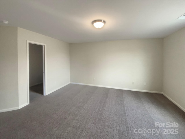 spare room with dark colored carpet and baseboards