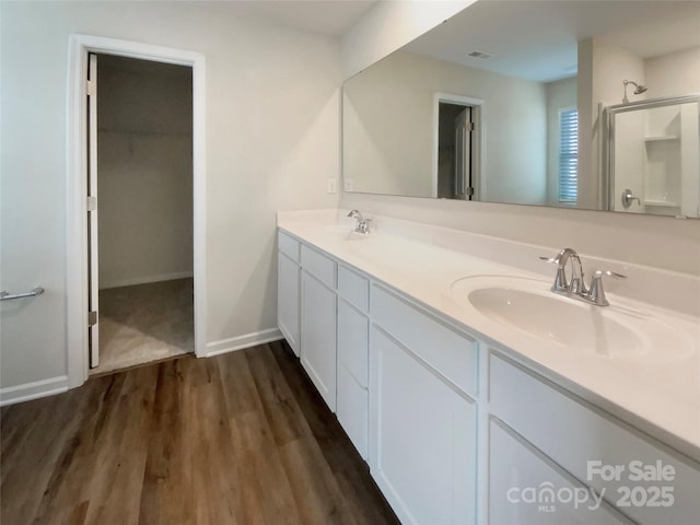 bathroom featuring double vanity, wood finished floors, a sink, and baseboards