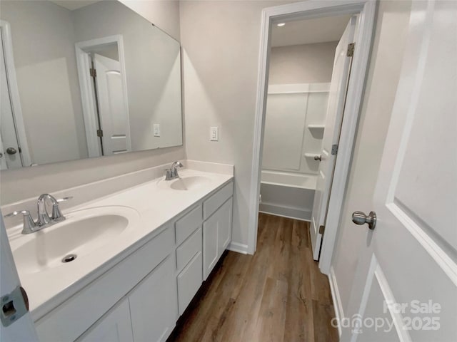 full bathroom featuring double vanity, a sink, and wood finished floors