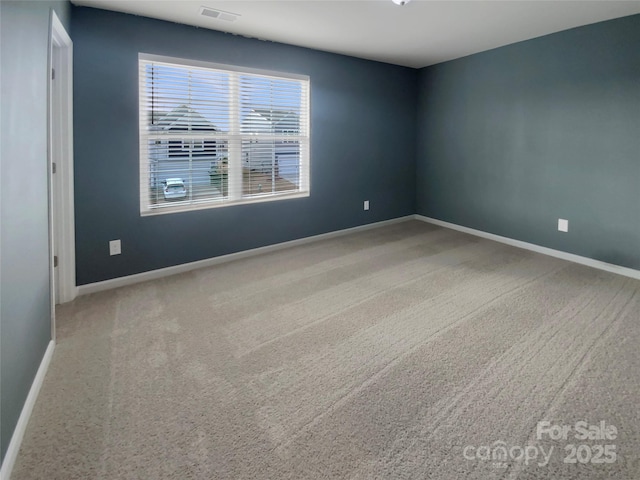 spare room with carpet, visible vents, and baseboards