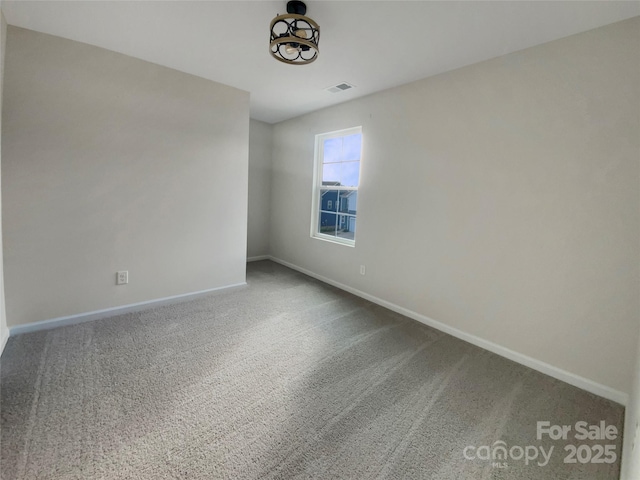 spare room with carpet floors, visible vents, and baseboards