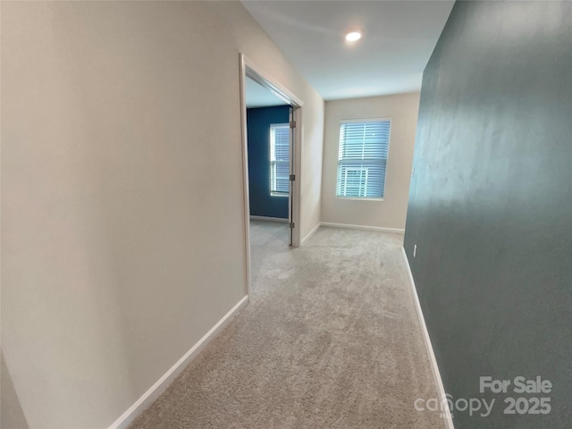 corridor featuring light carpet and baseboards