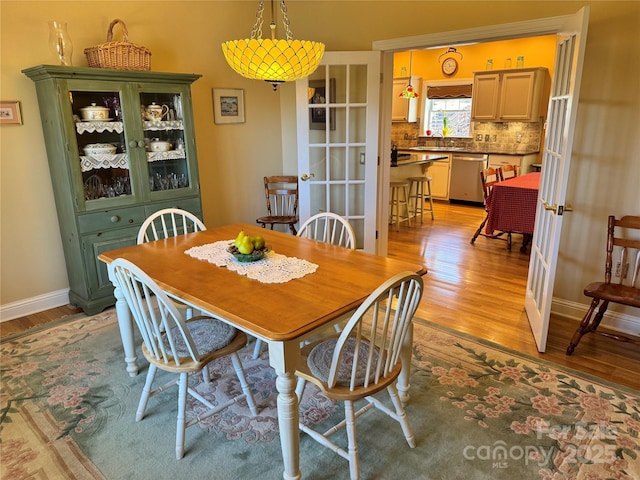 dining space featuring light wood-style flooring, baseboards, and french doors