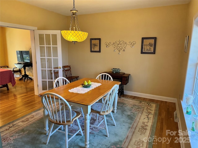 dining space with baseboards and wood finished floors