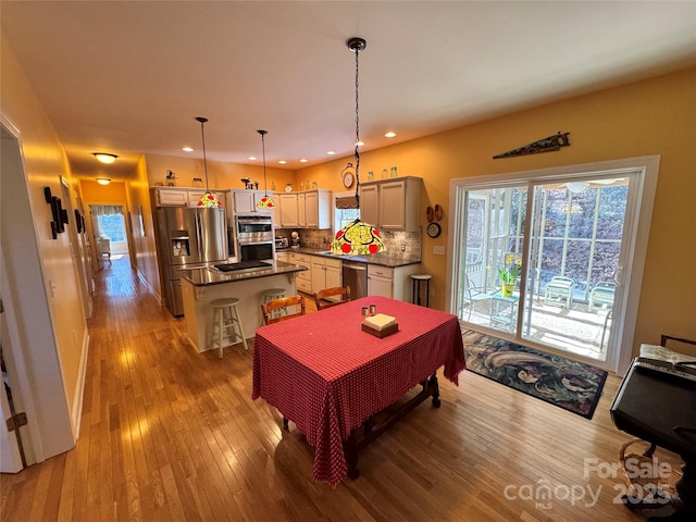 kitchen featuring a center island, a breakfast bar, stainless steel appliances, dark countertops, and hanging light fixtures