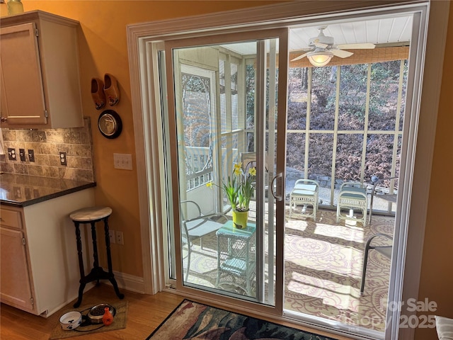 doorway to outside with ceiling fan, light wood-type flooring, and baseboards