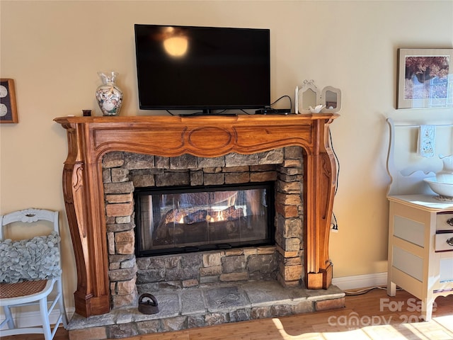 room details featuring a fireplace, baseboards, and wood finished floors