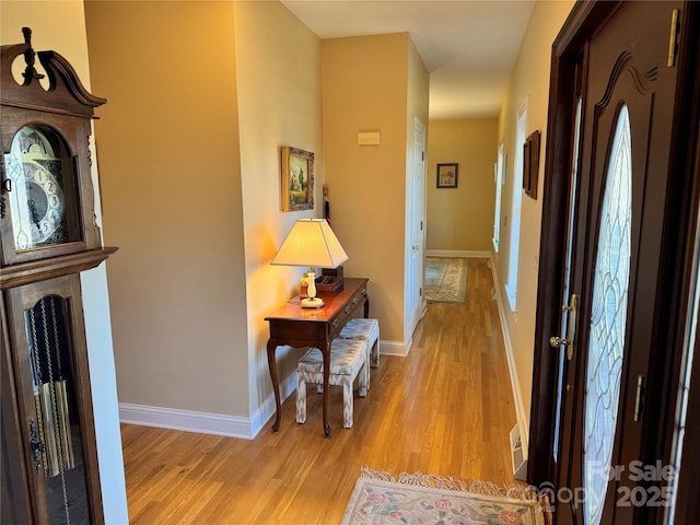 corridor featuring light wood-type flooring and baseboards