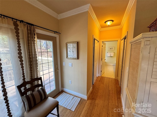 interior space featuring light wood-style floors, crown molding, and baseboards