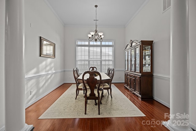 dining area with dark wood-style floors, crown molding, visible vents, and a notable chandelier