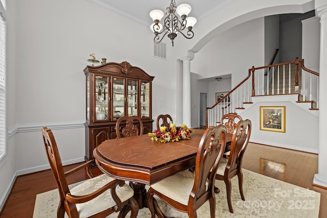 dining area featuring decorative columns, crown molding, visible vents, and wood finished floors