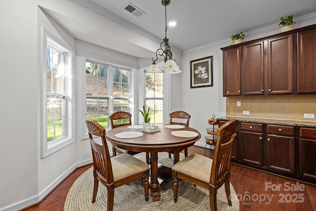 dining room featuring crown molding, dark wood finished floors, visible vents, and baseboards