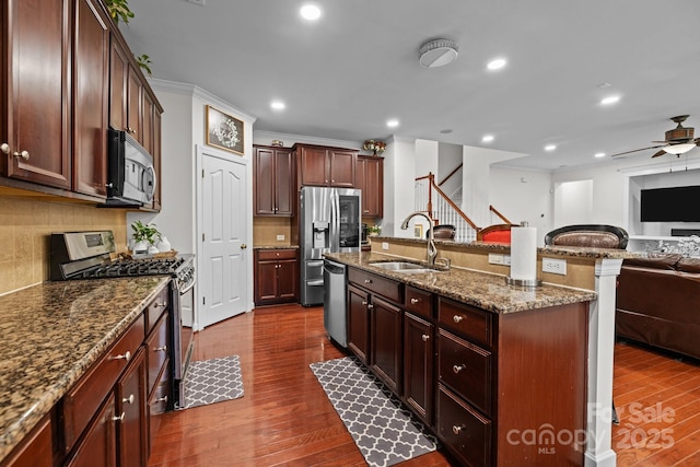 kitchen with a center island with sink, dark wood finished floors, appliances with stainless steel finishes, open floor plan, and a sink