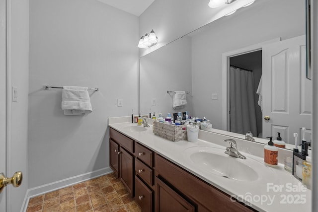 bathroom featuring a sink, baseboards, and double vanity