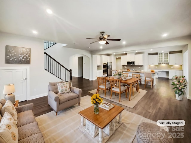 living room featuring arched walkways, recessed lighting, wood finished floors, a ceiling fan, and stairs