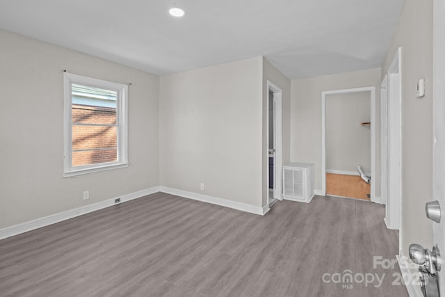 spare room featuring wood finished floors, visible vents, and baseboards