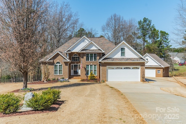 view of front of home with a garage, brick siding, concrete driveway, and fence