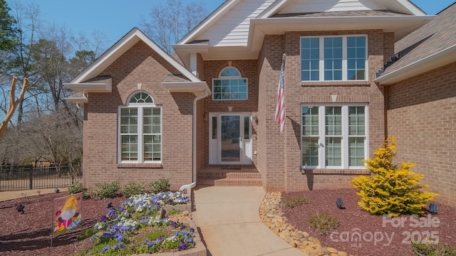 view of front of home with brick siding and fence