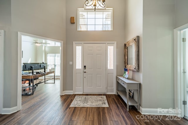 entryway featuring baseboards, dark wood-type flooring, and a high ceiling