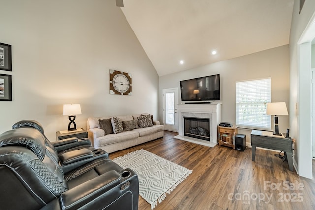 living room with a premium fireplace, recessed lighting, high vaulted ceiling, and wood finished floors