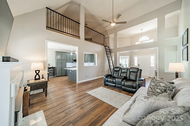 living room with high vaulted ceiling, a ceiling fan, baseboards, and wood finished floors