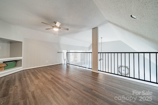 additional living space with baseboards, ceiling fan, vaulted ceiling, wood finished floors, and a textured ceiling