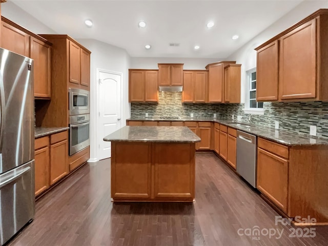 kitchen featuring under cabinet range hood, a kitchen island, appliances with stainless steel finishes, and dark wood-style floors