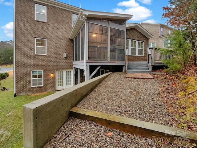 back of house with a sunroom, brick siding, and a yard