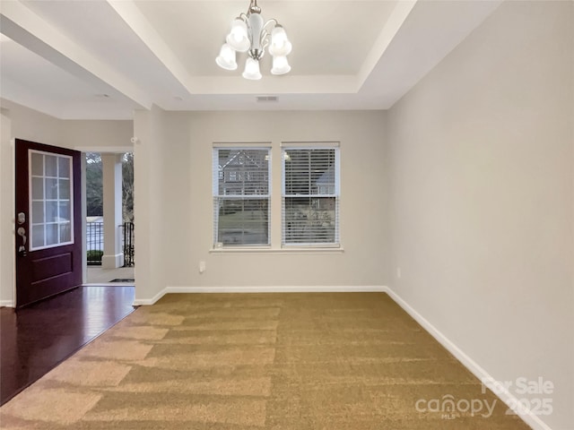 unfurnished room featuring a chandelier, a tray ceiling, a healthy amount of sunlight, and baseboards