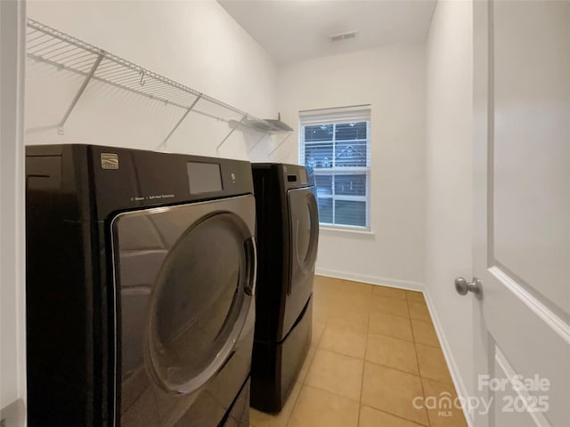 washroom featuring light tile patterned floors, laundry area, visible vents, baseboards, and washer and clothes dryer