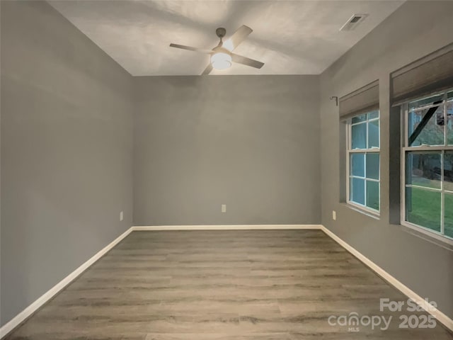 spare room featuring a ceiling fan, wood finished floors, visible vents, and baseboards