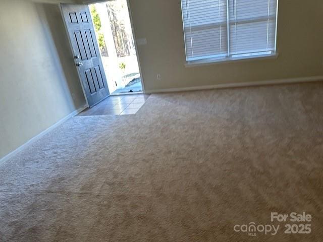 foyer entrance featuring light carpet and baseboards