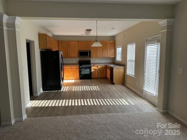 kitchen featuring wood finished floors, a sink, baseboards, hanging light fixtures, and black appliances