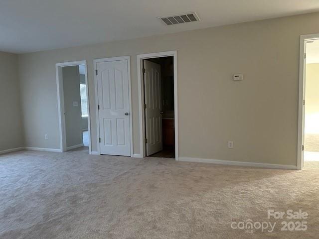 empty room with baseboards, visible vents, and light colored carpet