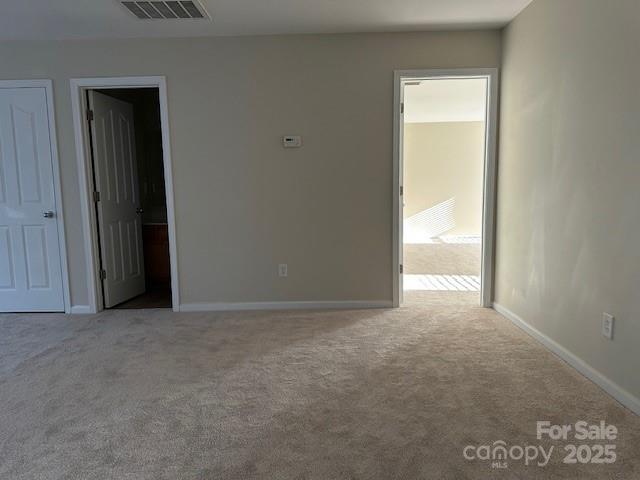 unfurnished room featuring light carpet, visible vents, and baseboards